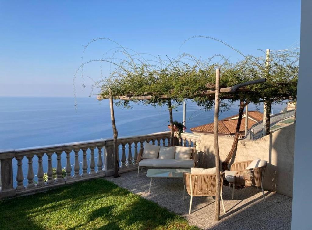 a patio with a couch and chairs on a balcony at Belvedere Amodeo - terrace, seaview, wifi in Conca dei Marini