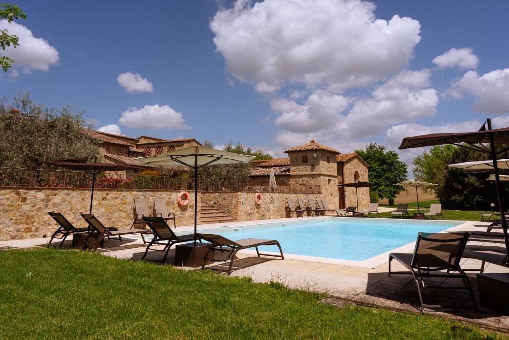 a pool with chairs and umbrellas next to a building at Villa Le Beringhe - Wine Pool & Relax in Colle Val D'Elsa