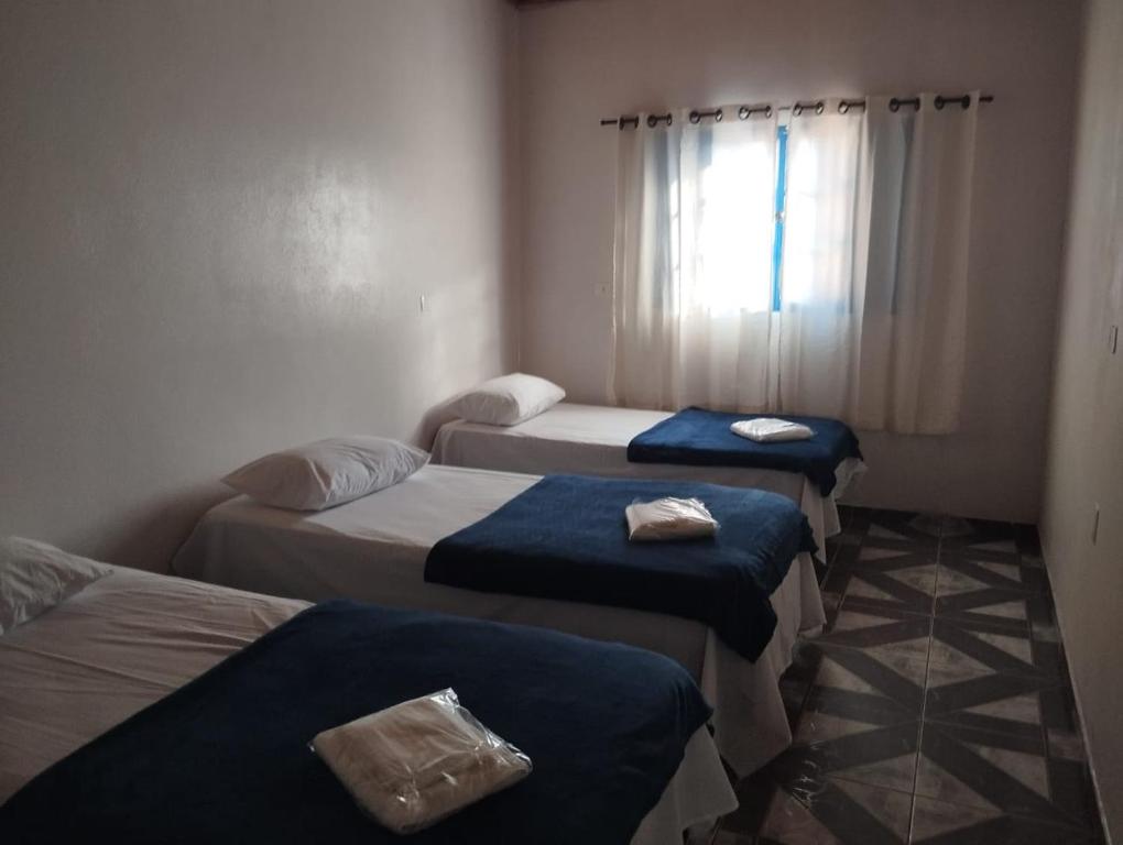 Zimmer mit 4 Betten, blauer Bettwäsche und einem Fenster in der Unterkunft Pousada Li Art in Itapeva