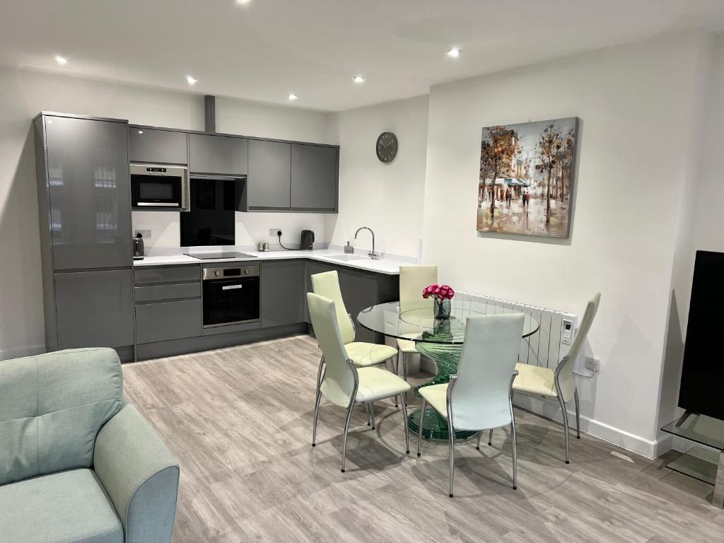cocina y comedor con mesa de cristal y sillas en El Murrino Apartments, en Bournemouth