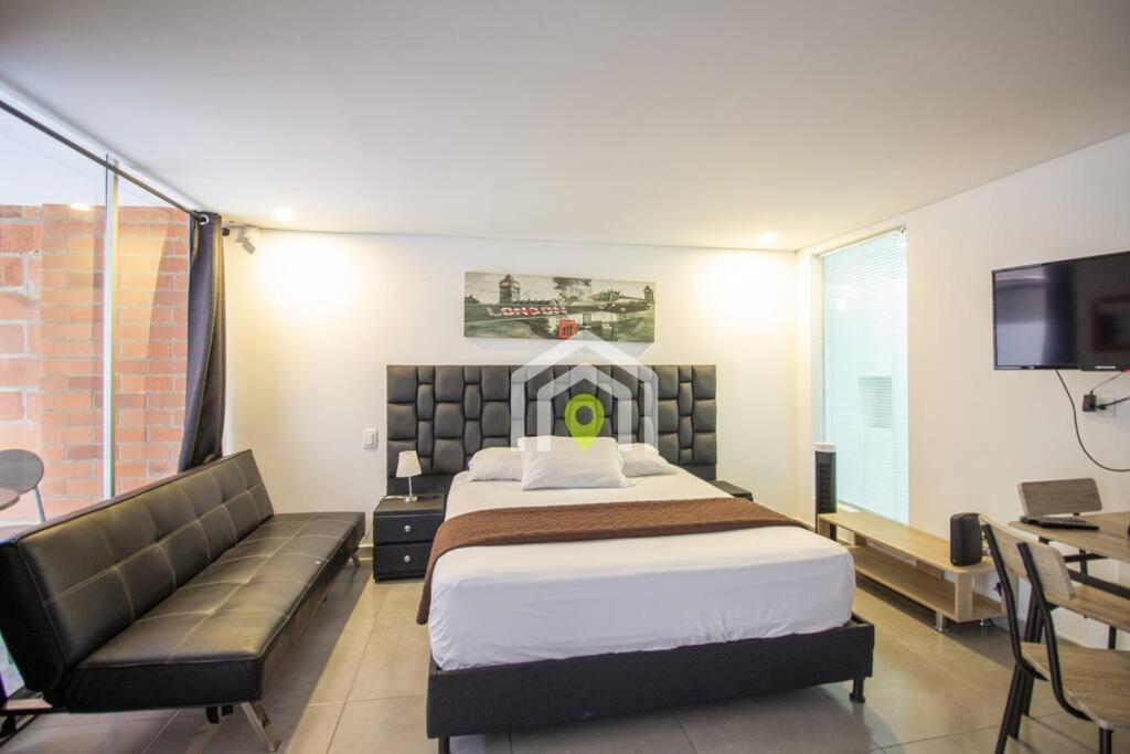 ein Schlafzimmer mit einem Bett, einem Sofa und einem TV in der Unterkunft Avenida el poblado La frontera con terraza in Medellín