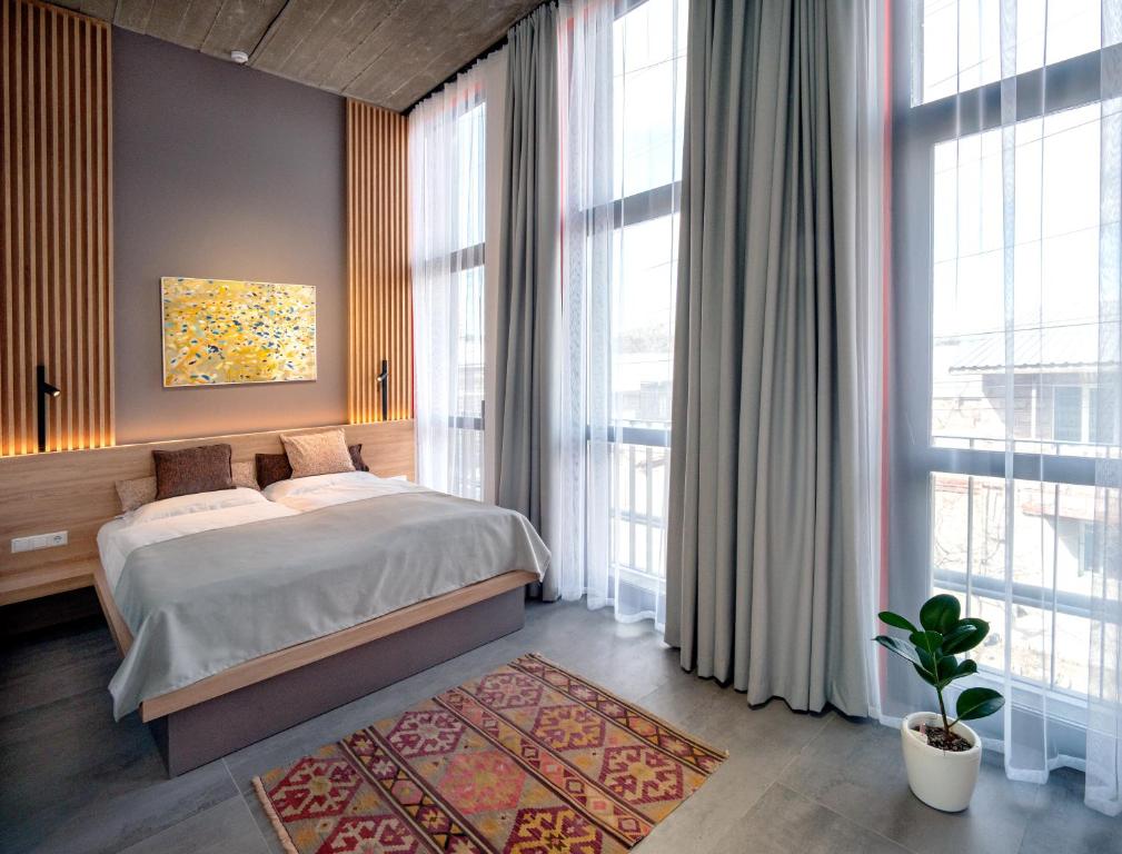 a bedroom with a bed and large windows at Erkan Alek Heritage Hotel in Gyumri