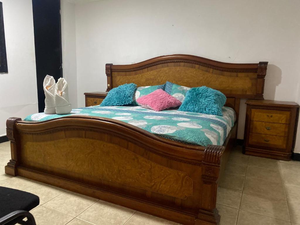 una cama de madera con almohadas coloridas. en Hotel Estadio Suite, en Medellín
