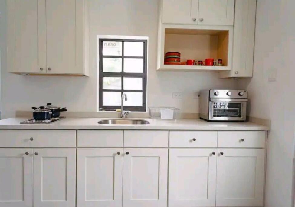 een keuken met witte kasten, een wastafel en een magnetron bij Studio Soliá-Slice Of Paradise in Bridgetown
