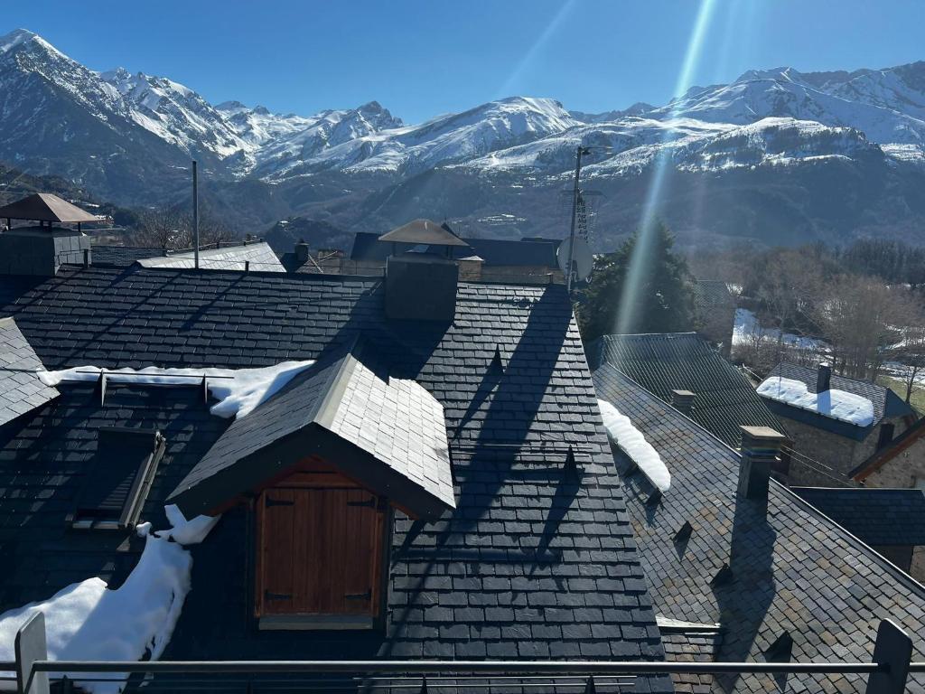 a roof of a house with snowy mountains in the background at CASA PELENTOS Sandinies in Sandiniés