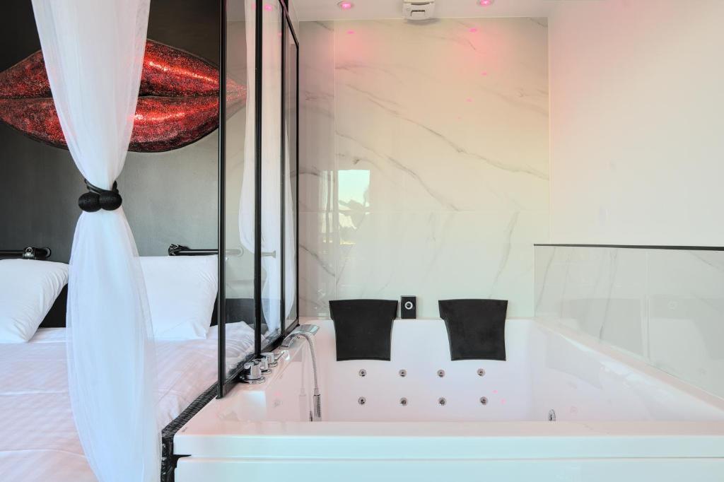 uma casa de banho branca com uma banheira e uma cama em Le balcon romantique em Metz