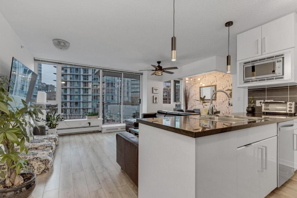 uma cozinha com armários brancos e uma grande janela em Gastown Downtown Apartment very central em Vancouver