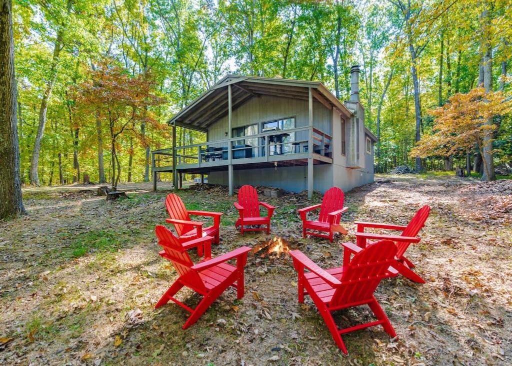 a group of red chairs around a fire in front of a house at Cabin w Hot Tub, Huge Deck, Firepit & WiFi! in Hedgesville