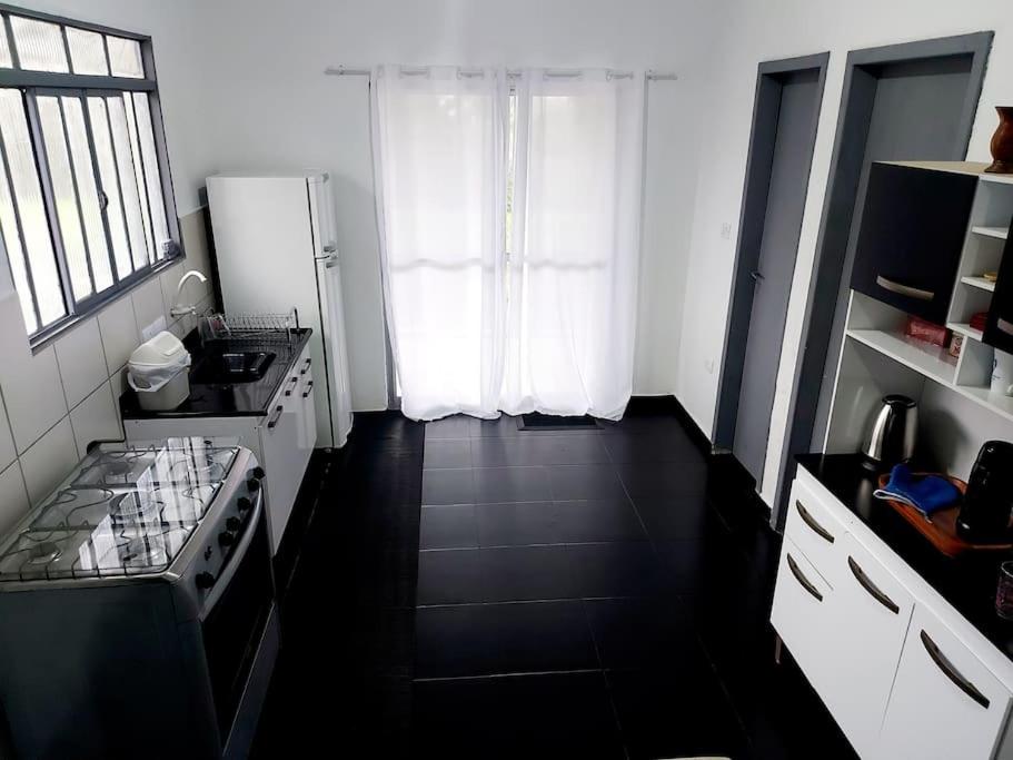 Il dispose d'une cuisine avec un réfrigérateur blanc et un sol noir. dans l'établissement Casa inteira em chácara, 20 min centro., à Curitiba