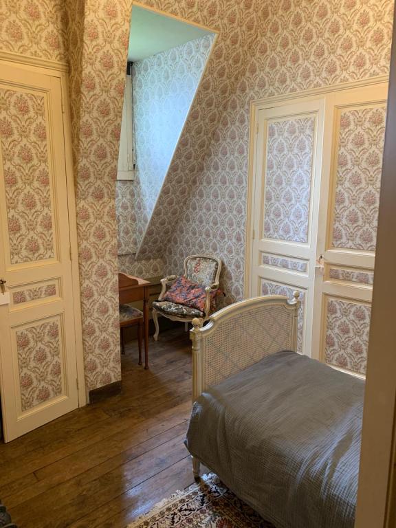 een slaapkamer met een bed en een stoel in een kamer bij Château de la Franceule - la petite in Janzé