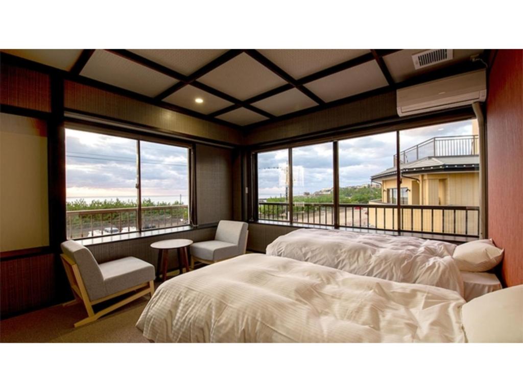 a bedroom with two beds and a balcony with windows at Taiheian - Vacation STAY 57429v in Sakai