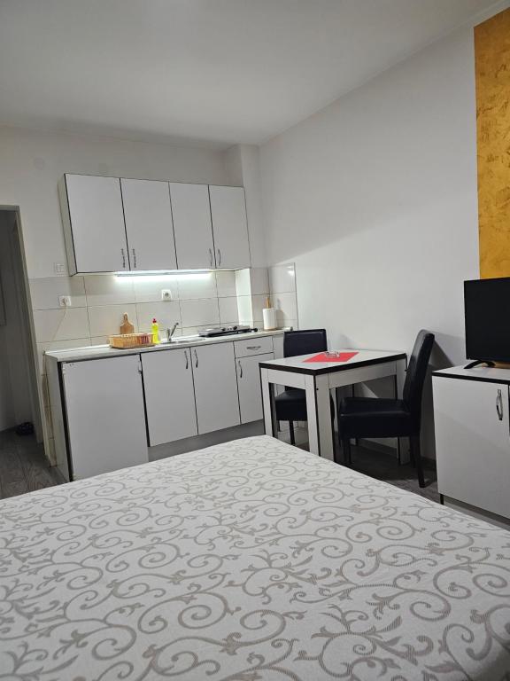 una cucina con mobili bianchi, tavolo e sedie di Apartmani Borko 3-1 a Loznica
