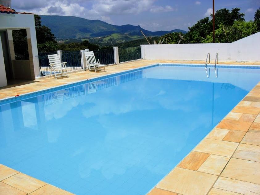 una gran piscina azul con 2 sillas de césped en Sua casa na Serra da Mantiqueira. 1h de SP en Extrema
