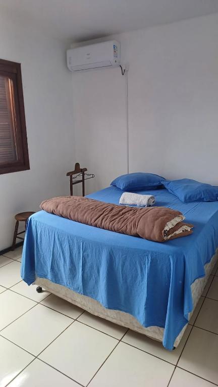 a bed in a room with a blue blanket on it at Quarto c/ Ar Split 01 cama casal , banheiro social compartilhado ( fora do quarto ) in Tabapira