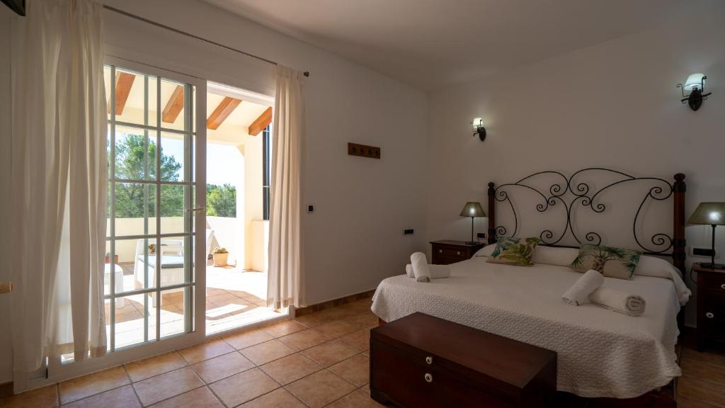 a bedroom with a bed and a sliding glass door at Apartaments ES POU in Sant Ferran de Ses Roques