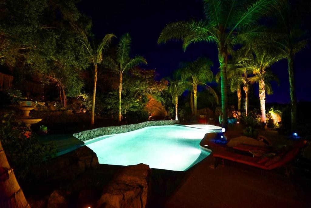 a large swimming pool with palm trees at night at The Malibu Retreat Private Compound w/ Salt Water Pool + Views in Malibu