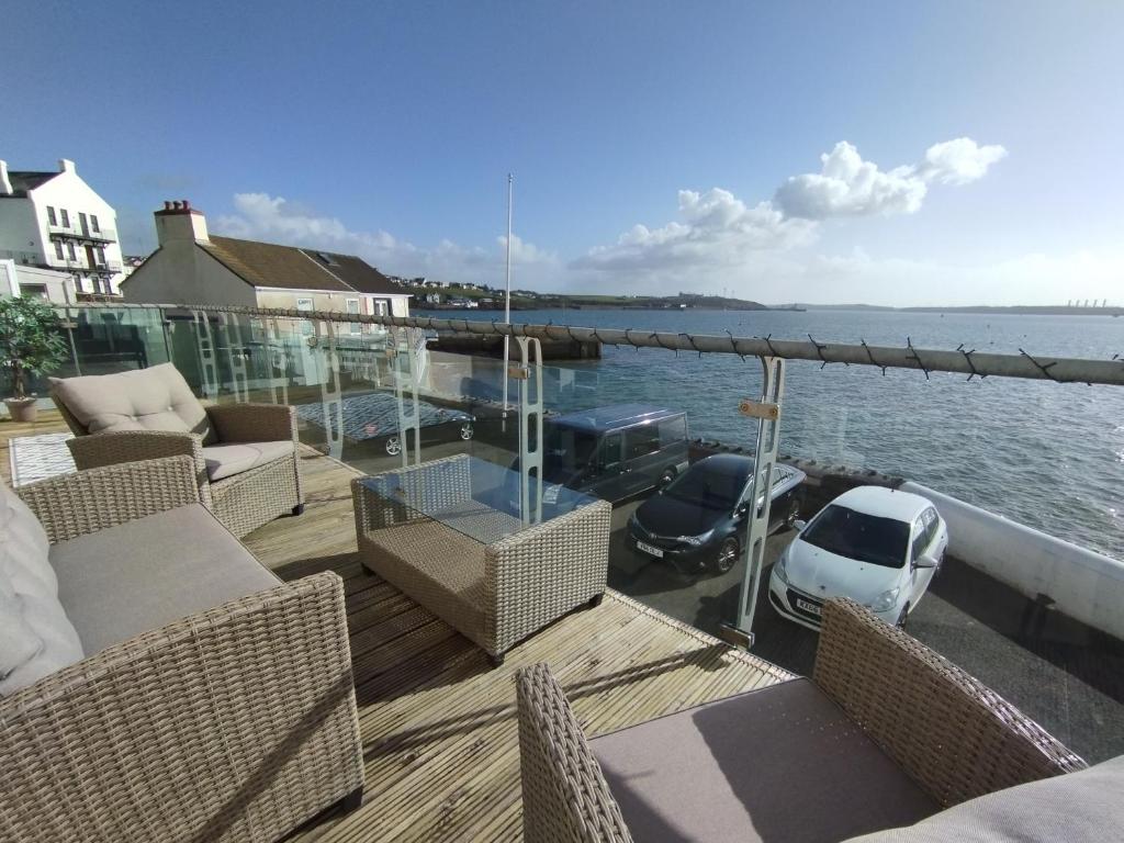 a deck with chairs and a car parked on the water at Old Castle in Pembrokeshire