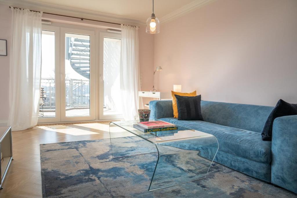 a living room with a blue couch and a glass table at C-Level Studios Studio I mit E-Ladesäule in TG in Hamburg