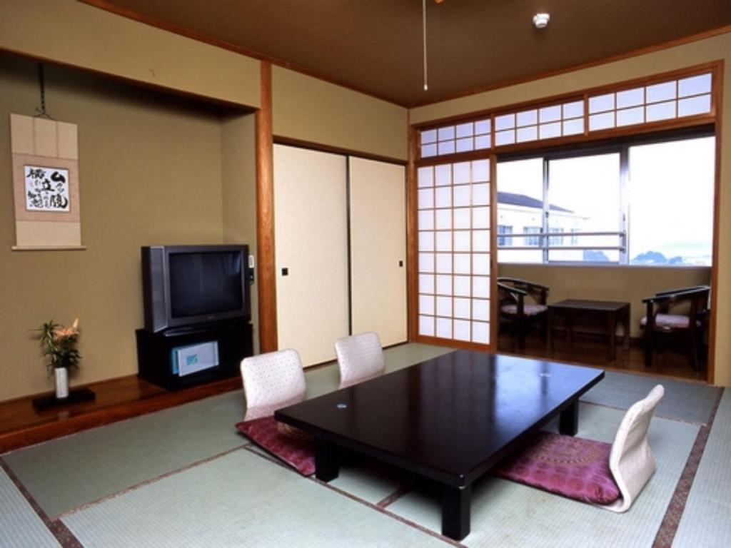 a living room with a table and chairs and a television at Matsushima Kanko Hotel Misakitei - Vacation STAY 22872v in Kami Amakusa