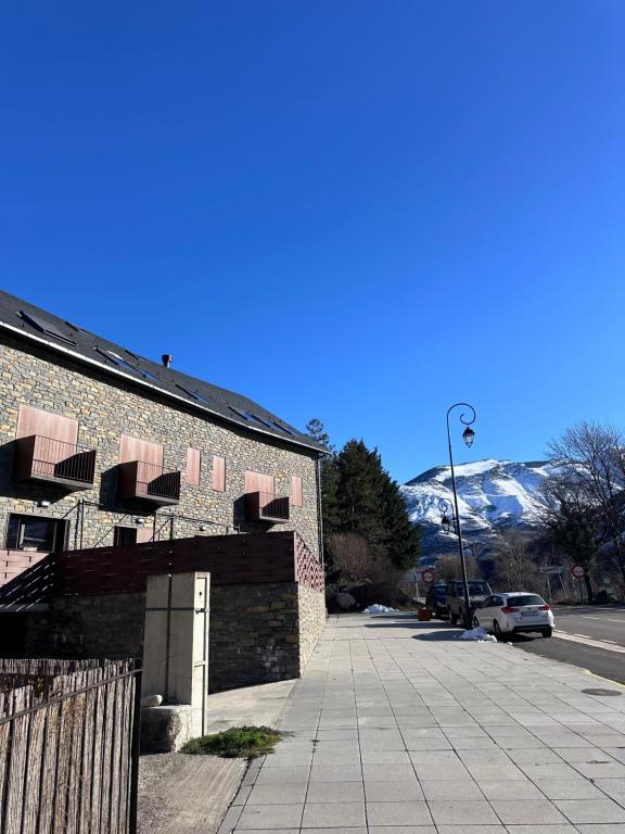 a brick building with snow covered mountains in the background at Can Lasai in Barruera