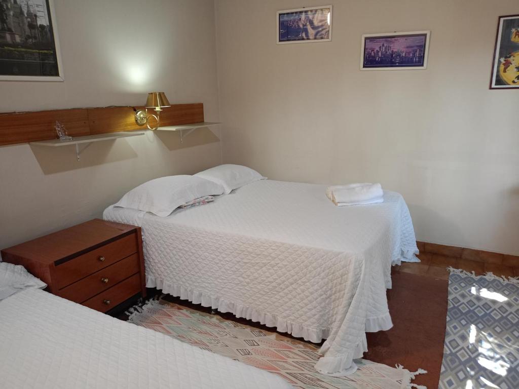 a bedroom with two beds with white sheets and a lamp at RESIDENCIA-UNIV in Ciudad del Este