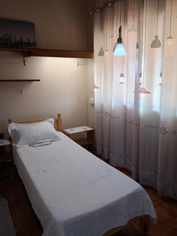 a bedroom with a bed with white sheets and curtains at RESIDENCIA-UNIV in Ciudad del Este