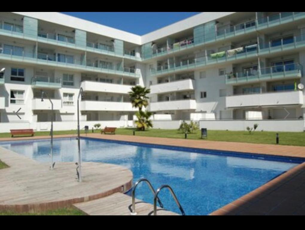 une piscine en face d'un grand bâtiment dans l'établissement Roses Espagne 4/5 pers piscine - plage, à Roses
