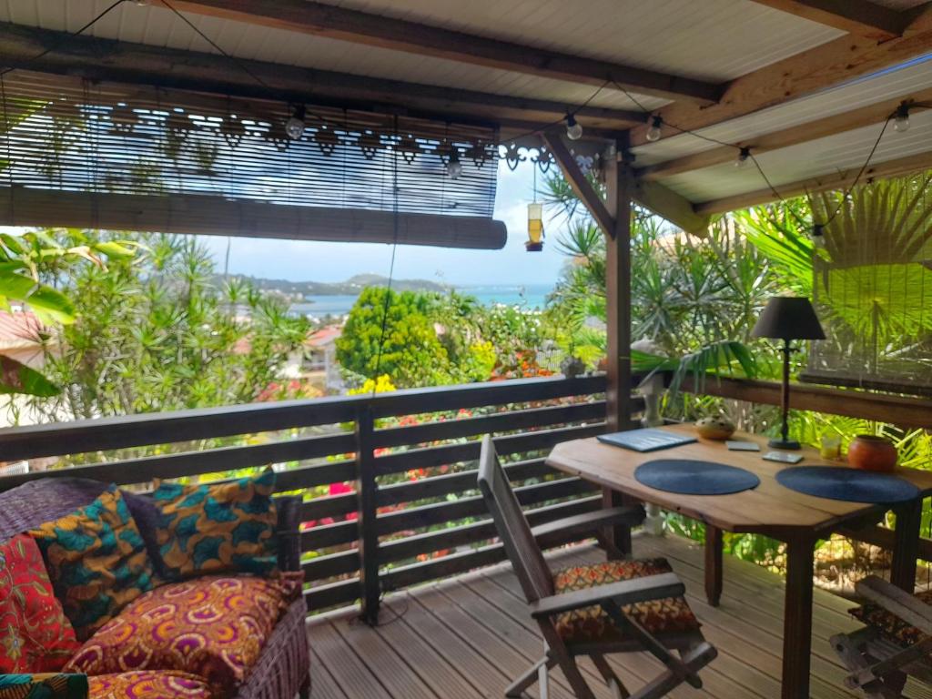 un patio con mesa y sillas en una terraza en Studio Bwa Banbou dans Villa Fleurs des Iles, en Le Vauclin