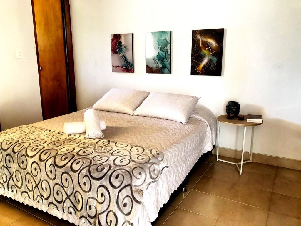 a bedroom with a bed and three paintings on the wall at Casa Río donde guardamos un secreto encantador in Montería
