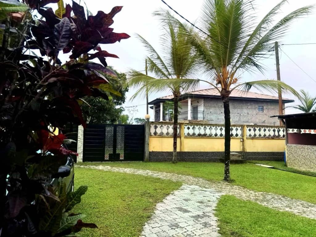 een huis met een geel hek en palmbomen bij residence des coeurs gabriella in Kribi