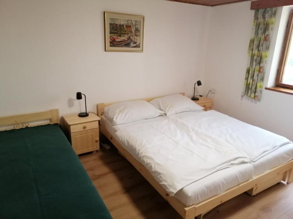 a bedroom with a white bed and two night stands at Chata U Selské rokle in Doksy