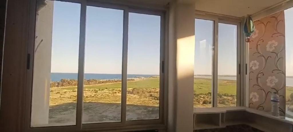 um quarto com três janelas com vista para o oceano em Hergla Sea view apartment & room em Harqalah