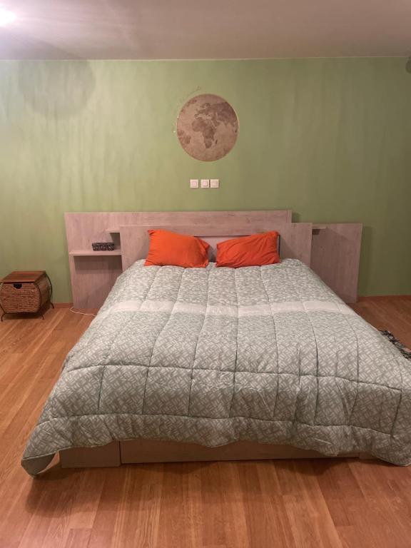 um quarto com uma cama grande e 2 almofadas laranja em Chambre verte spacieuse côté aéroport em Pusignan