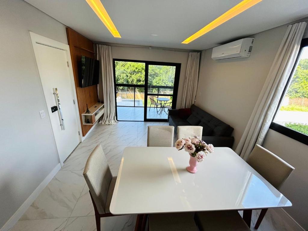 a white table with a vase of flowers on it at Lindo apartamento a 400 metros da praia com selo azul de qualidade in Governador Celso Ramos