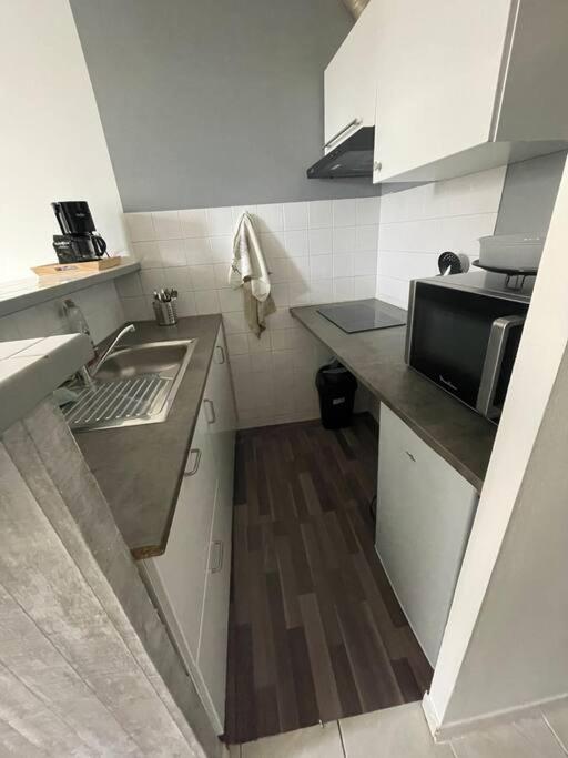 une petite cuisine avec un évier et un micro-ondes dans l'établissement Charmant appartement, à Saint-Thibéry