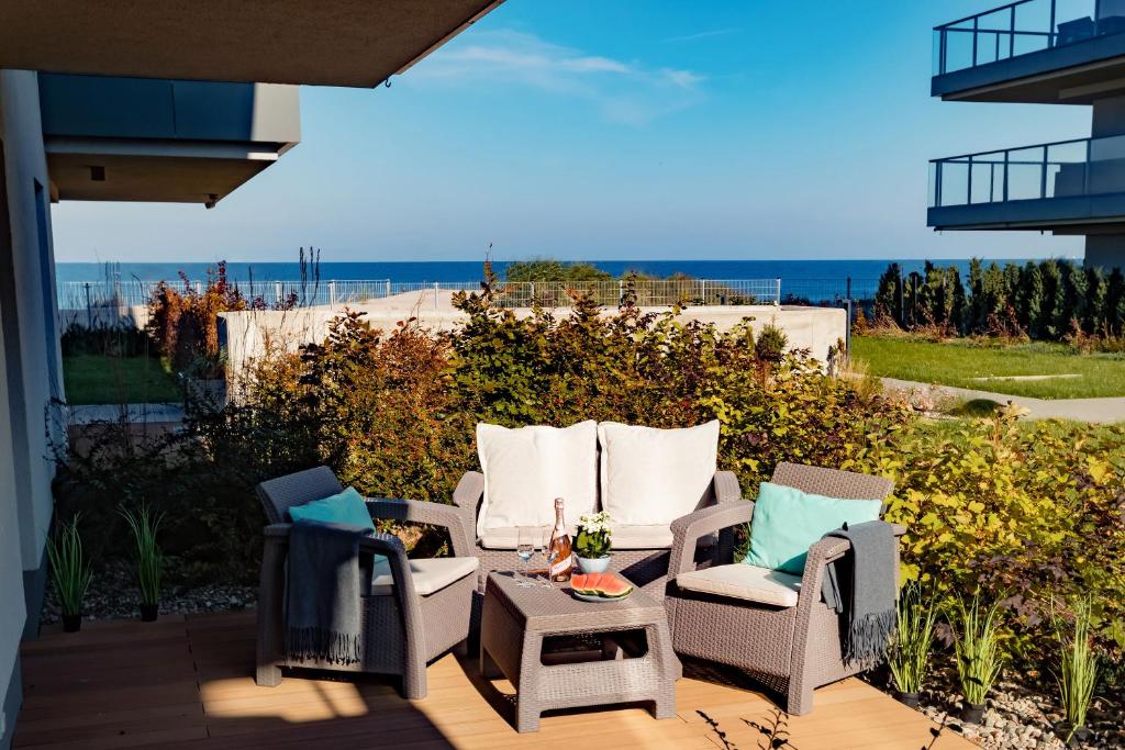 un patio con sillas, una mesa y el océano en Apartament Siesta z widokiem na morze w Gardenia Dziwnów, en Dziwnów