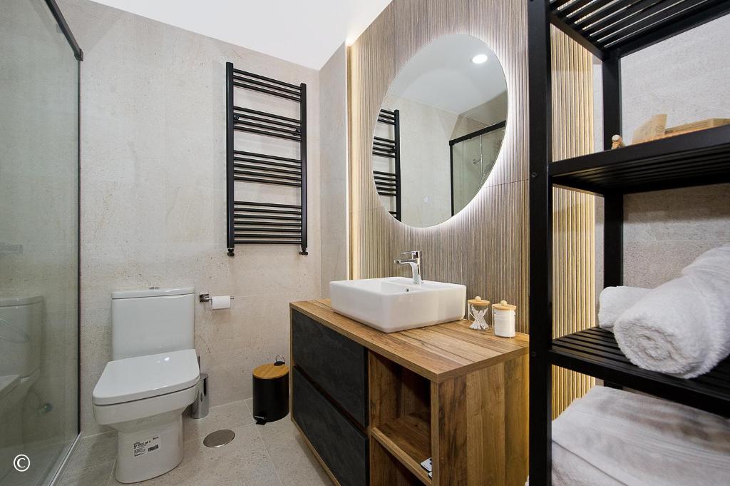 ein Badezimmer mit Waschbecken, Toilette und Spiegel in der Unterkunft Costa Calma y Relax in Santander