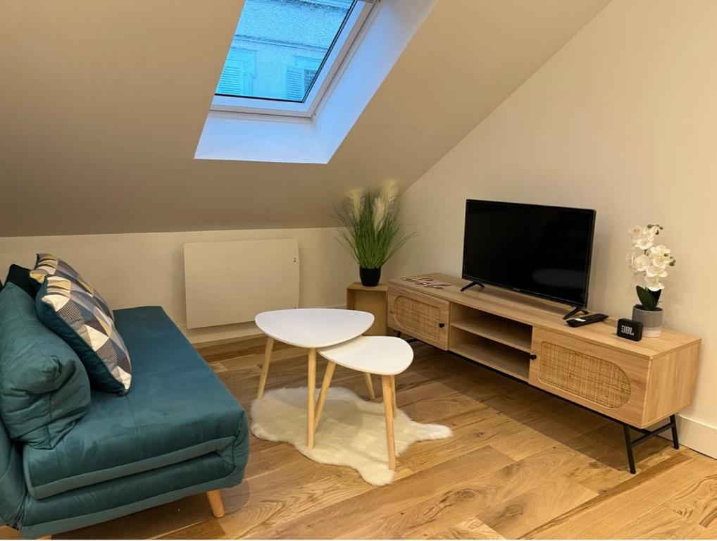un salon avec un canapé, une télévision et une table dans l'établissement Appartement Lou, hyper centre, au cœur de Troyes, à Troyes