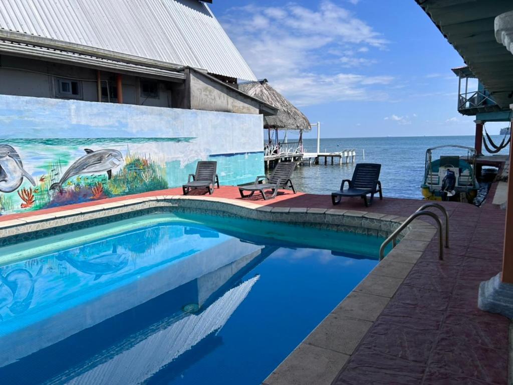 una piscina frente a un edificio con el océano en Hotel El Delfin, en Lívingston