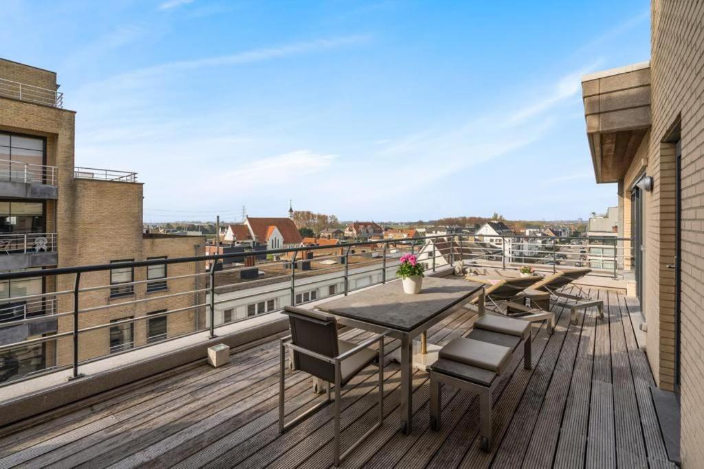 una terrazza in legno con tavolo e sedie sul balcone. di Ruim appartement met heerlijk zonneterras a Bruges