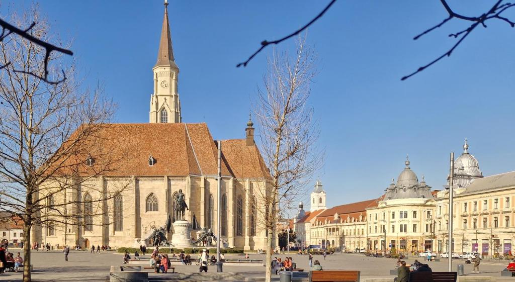 um grande edifício com uma igreja com uma torre de relógio em 5* Royal House near Unirii Square em Cluj-Napoca