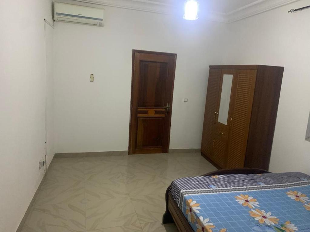 sypialnia z łóżkiem i drewnianymi drzwiami w obiekcie Appartement Mamy w mieście Dakar