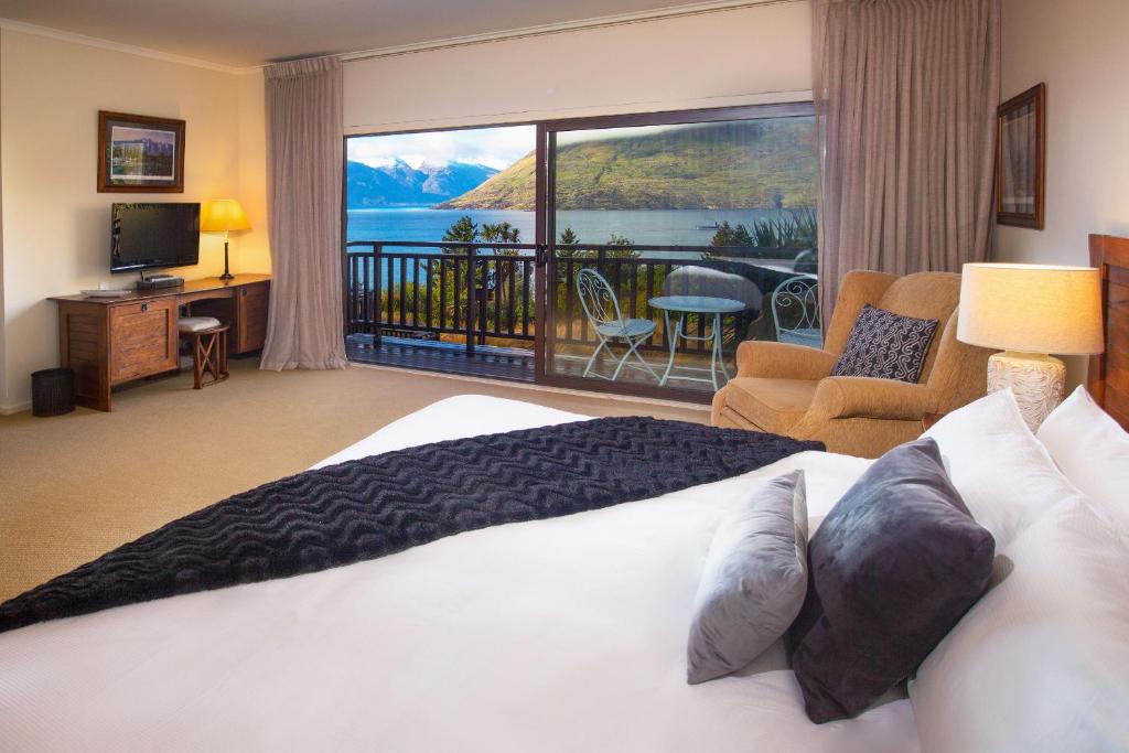 a bedroom with a bed and a balcony with a view at Hidden Lodge Queenstown in Queenstown