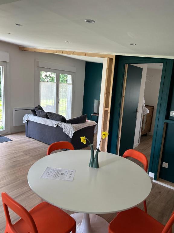 ein Wohnzimmer mit einem weißen Tisch und roten Stühlen in der Unterkunft La maison du jardin in Douai