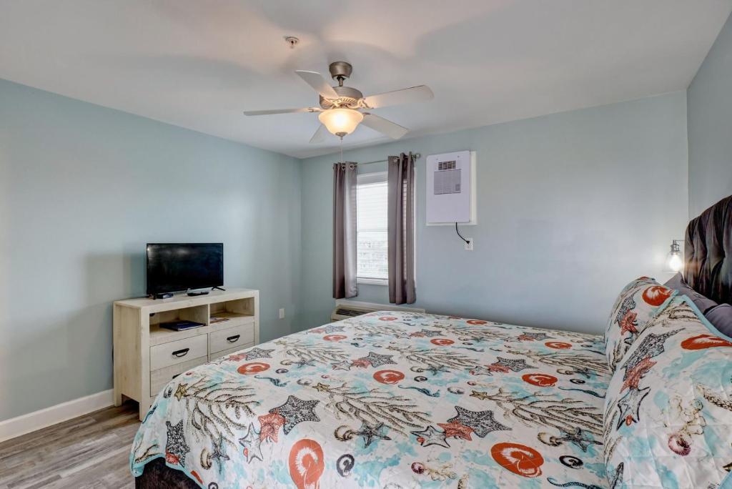 een slaapkamer met een bed en een plafondventilator bij Unit 08 at Tiffany's in Surf City