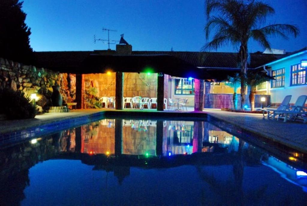 a swimming pool in a house at night at Oasis Country Lodge in Klawer