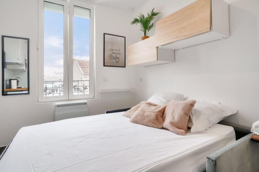 a bedroom with a large white bed with two windows at Studette 4 calme et Lumineux, entièrement équipée in Créteil