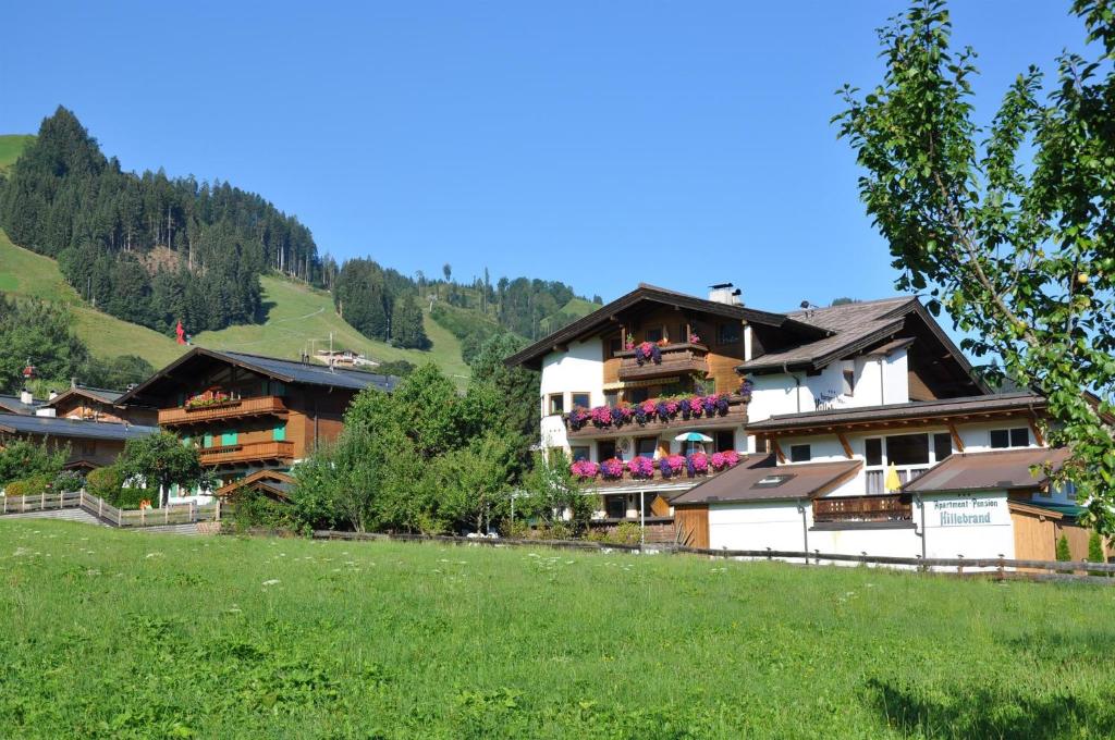 a building on a hill with a green field at Apartmentpension Hillebrand in Kitzbühel