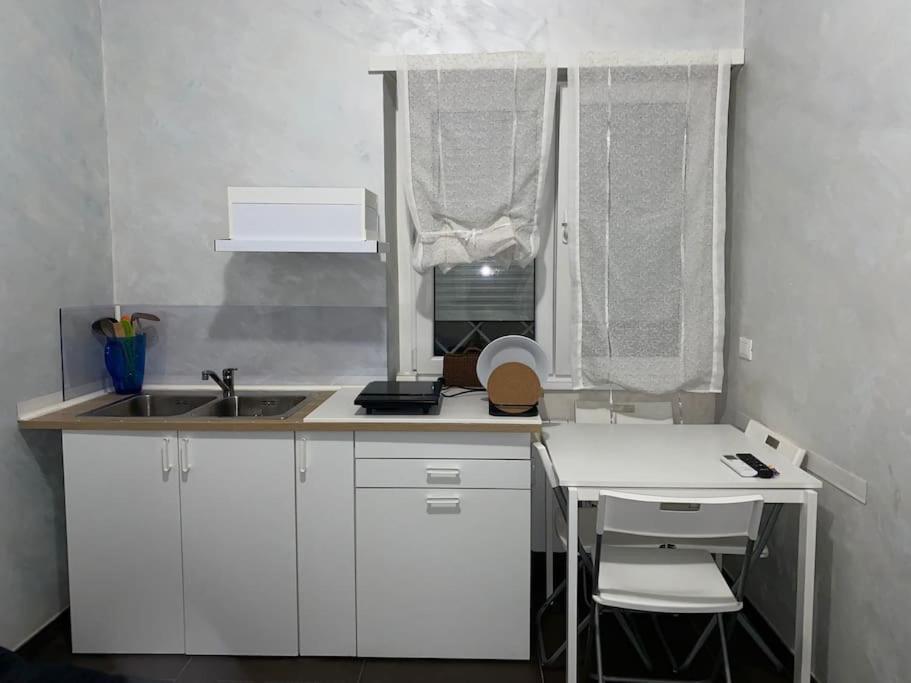 una pequeña cocina blanca con fregadero y mesa en CS LUXURY HOUSE 2.0, en Lido di Ostia