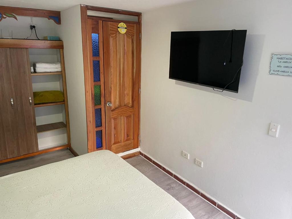 um quarto com uma cama e uma televisão de ecrã plano na parede em Habitación La Amelia em Jericó